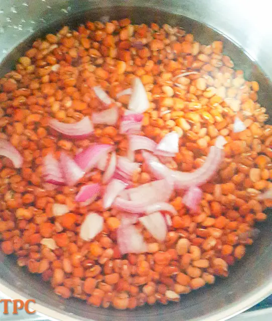 beans with sliced onions cooking in a pot for Adalu, beans and corn porridge