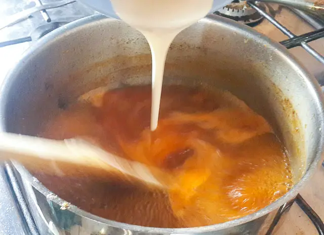 pouring corn paste into broth for agidi jollof