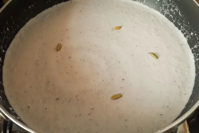 shredded coconut, coconut milk, cardamom in sauce pan for Indian coconut ladoo