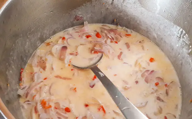 tomato, onions and pepper boiling in coconut milk for Nigerian Coconut Rice