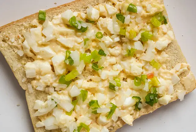 mashed egg and spring onions on a slice of bread for boiled egg sandwich