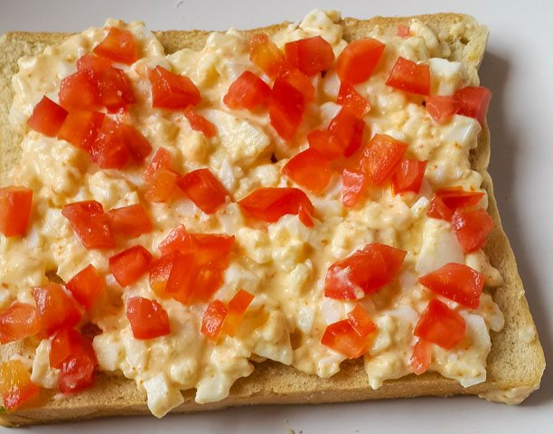 mashed egg and spring onions on a slice of bread for boiled egg sandwich