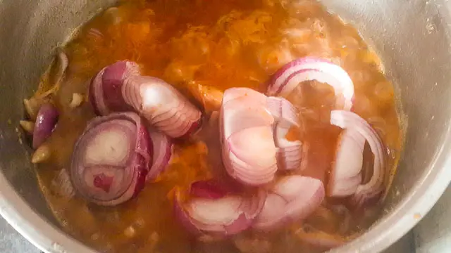 onion chunks being added to quick and easy tomato sauce in a pot