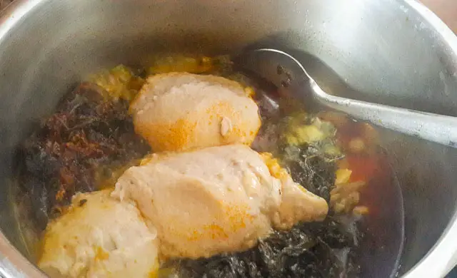 Bitter leaf soup (onugbu soup) in a pot with lumps of cocoyam