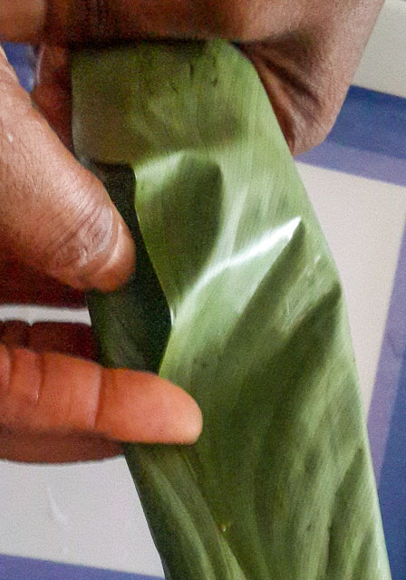 agidi jollof being wrapped in leaves