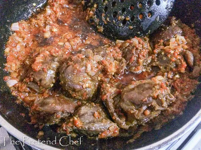 nigerian peppered gizzard frying in frying pan with peppers 