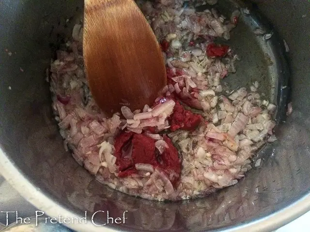 tomato puree added to frying onions in a pot for fresh tomato sauce