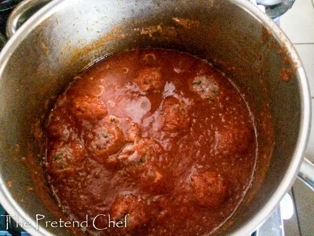 meatballs added to pot of fresh tomato sauce