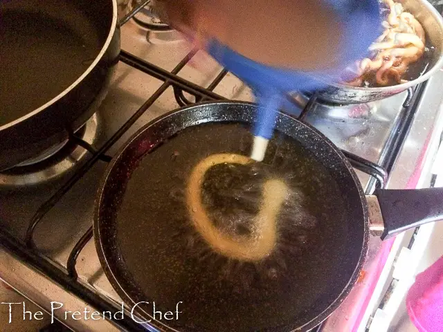 funnel cake batter being poured into hot oil
