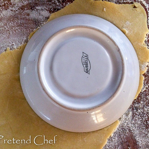 Nigerian meat pie dough being cut with a saucer