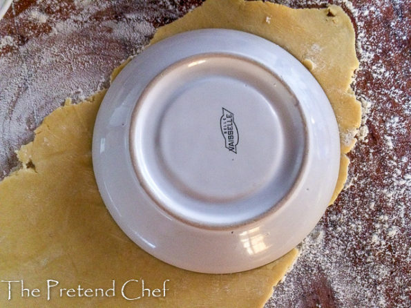 Nigerian meat pie dough being cut with a saucer