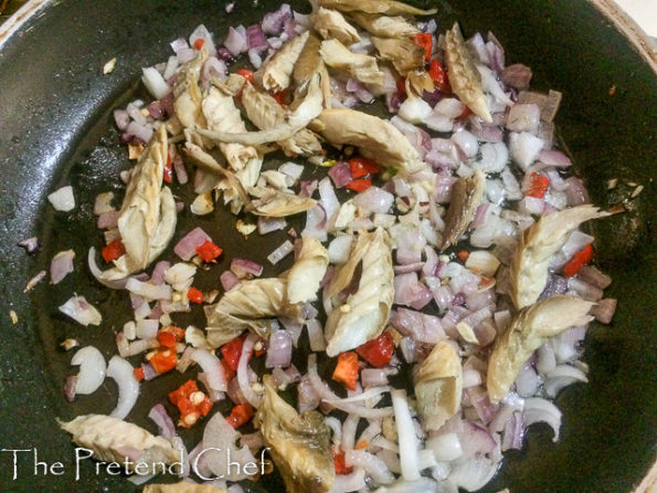 smoked fish with greens frying in a saucepan