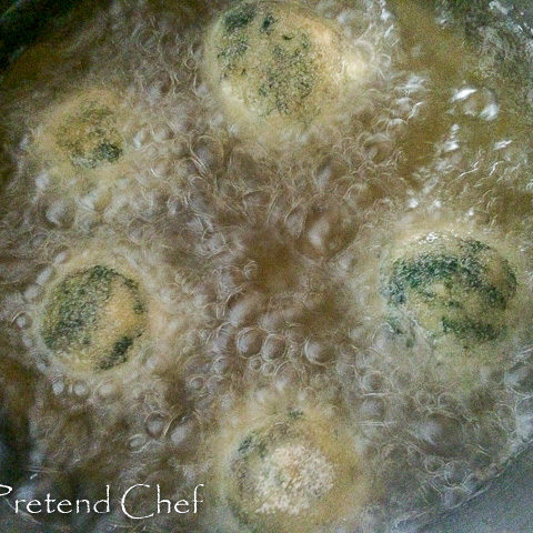 uncooked potato green vegetable balls frying in oil.