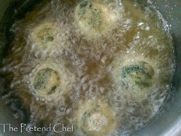 uncooked potato green vegetable balls frying in oil.