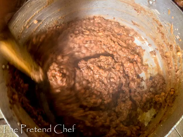 Oloyin beans being mashed in a pot for ewa agoyin