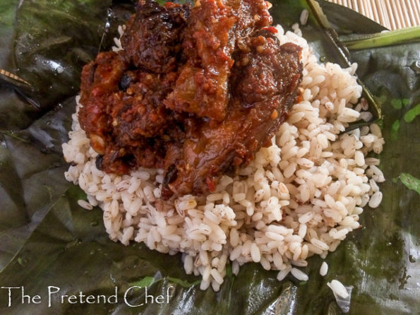 Hot and spicy ofada rice and stew served in fresh banana leaves