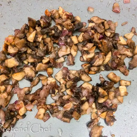 chopped mushrooms frying in a frying pan