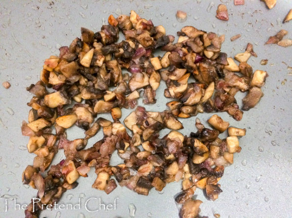 chopped mushrooms frying in a frying pan