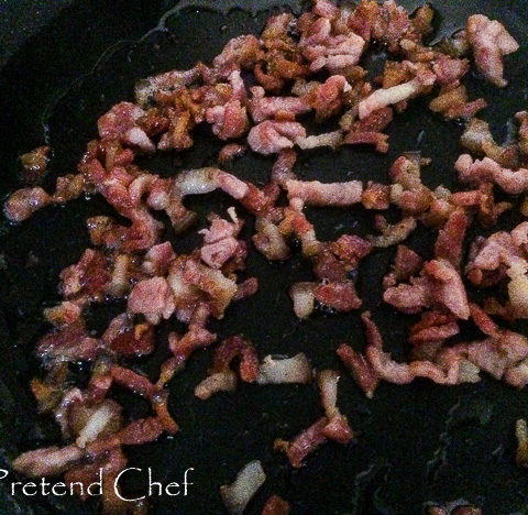 chopped bacon frying in a frying pan