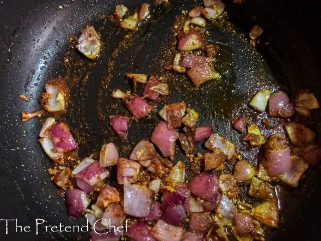 onions sauteing in a frying pan for Nigerian Tomato Rice recipe using leftover rice