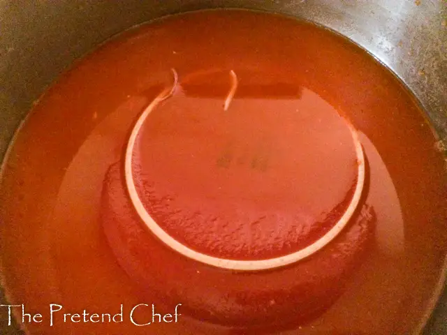plate pressing down Stuffed Cabbage roll in a pot with tomato sauce