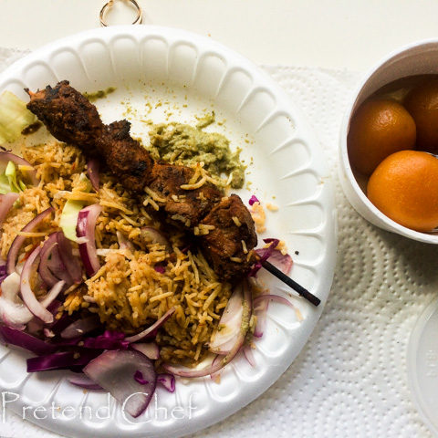 plate of rice skewered meat and gulab jamun