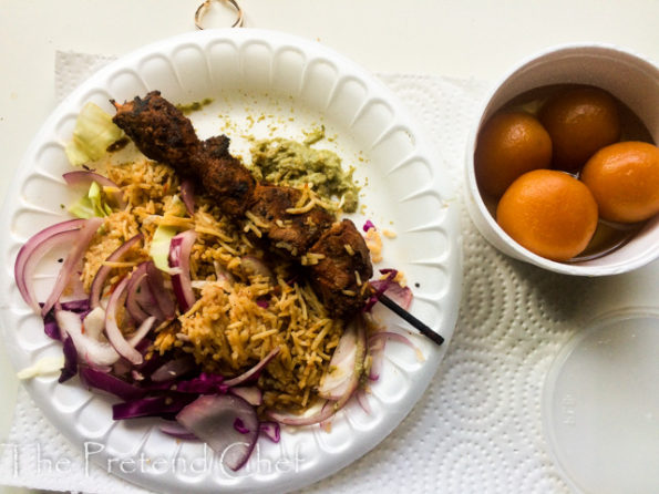 plate of rice skewered meat and gulab jamun