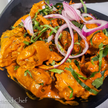 Nkwobi (cowleg) in a plate with red onions and utazi